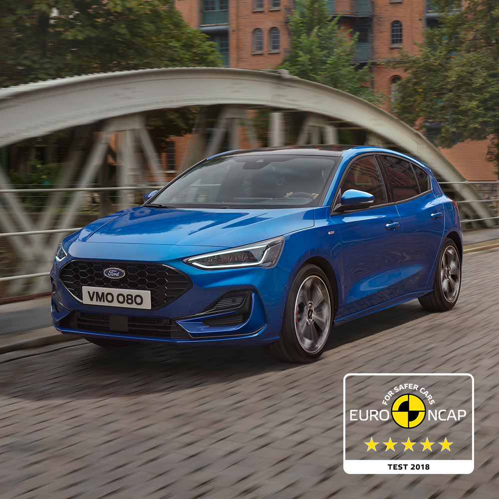 Un Ford Focus azul estacionado en un puente, con la insignia de calificación de seguridad Euro NCAP de cinco estrellas en la esquina inferior derecha.